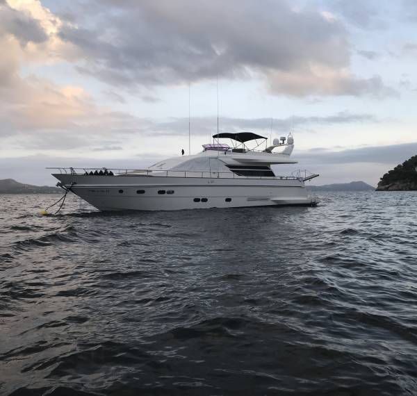 Stern of 70 ft Scapa luxury yacht charter docked at marina at dusk, large cockpit with swim platform and teak aft deck lit up