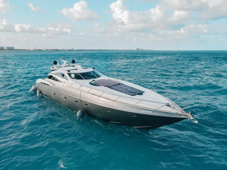 Aerial port-side view of 75 ft Sunseeker Predator luxury yacht charter anchored in open Caribbean sea with Cancun skyline in distance