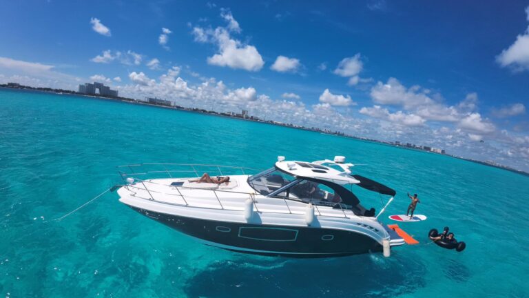 Yate Premier de 42 ft Itzae navegando junto a la atracción del barco pirata en la laguna de Cancún con invitados de pie en la proa disfrutando el paseo, casco negro y blanco reluciente