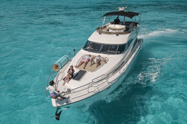 Stern transom of 45 ft Sealine Amasivar yacht charter at Puerto Juarez Cancun marina displaying Amasivar name and swim ladder, Cancun hotel zone skyline in background