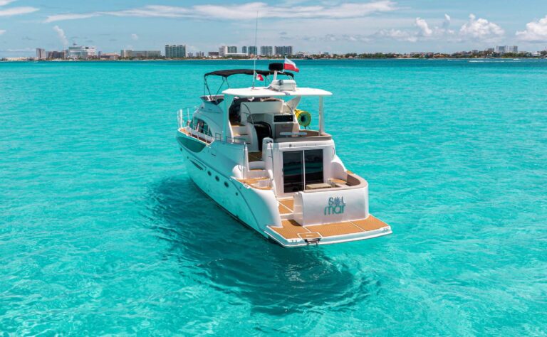 Vista trasera del yate charter Meridian Sol Mar 50 ft con timón Garmin, asientos grises acolchados en rombos y cubierta de teca en la marina de Cancún