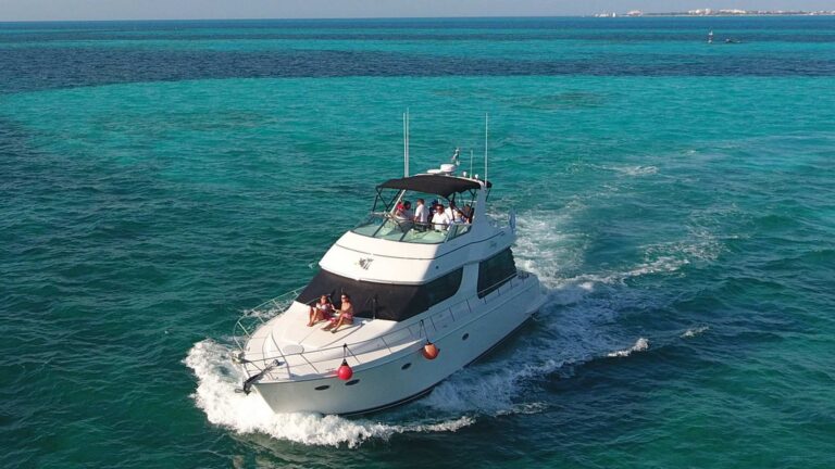 Vista cenital aérea del yate charter de lujo Carver Trilogy 55 ft fondeado en aguas turquesas cristalinas cerca de Isla Mujeres con jet ski junto a la popa