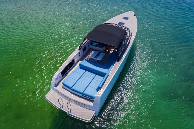 Wide aerial view of 40 ft VanDutch luxury charter boat anchored in crystal-clear turquoise Caribbean waters near sandy beach shoreline, Puerto Aventuras Riviera Maya