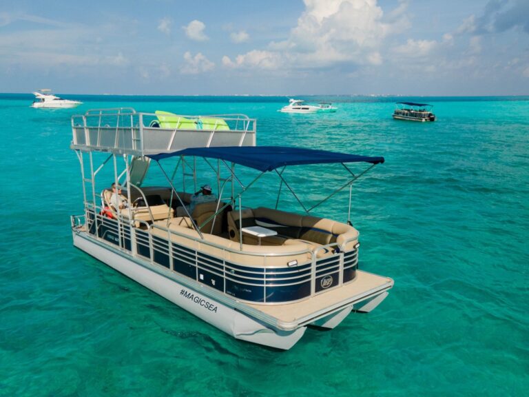 Aerial view of 33 ft Leisure Kraft double-deck pontoon boat charter anchored in turquoise Caribbean water near Cancun with green water slide and #MAGICSEA branding on hull