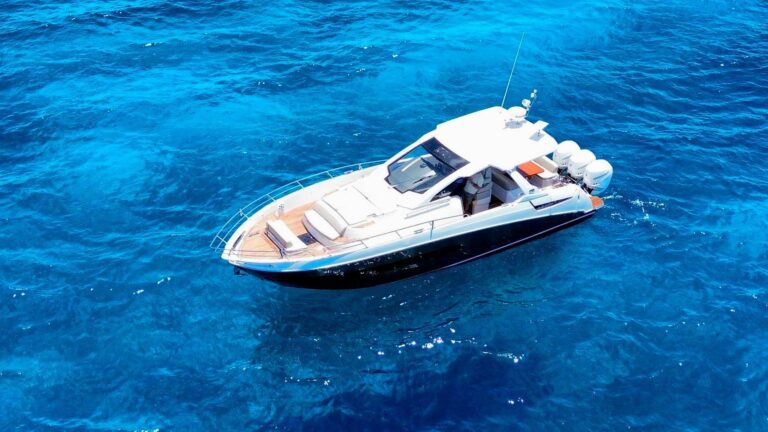 Aerial side view of 40 ft Azimut luxury yacht charter anchored in deep blue Cozumel open water showing full deck layout with teak bow sun pad and triple outboard motors