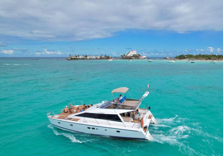 Catamarán de motor Cocoon 42 ft navegando por el Caribe turquesa cerca del emblema de Isla Mujeres, invitados relajándose en la amplia cubierta de teca, renta en Cancún