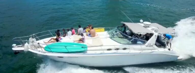 Vista aérea del yate de lujo Sea Ray Angelina 43 ft en navegación con un grupo grande de invitados en cubierta, tabla de surf y flotadores a bordo, mar Caribe, renta en Cancún