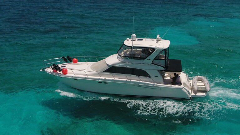 50 ft Sea Ray Flybridge luxury yacht charter cruising through turquoise Caribbean waters near Cancun with white wake trailing behind