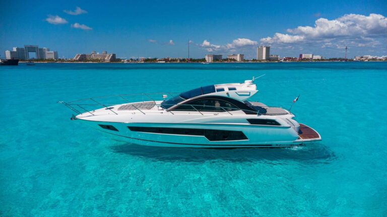 Starboard view of 53 ft Sunseeker San Remo luxury sport boat charter anchored in crystal turquoise Caribbean water with Cancun Hotel Zone skyline in background