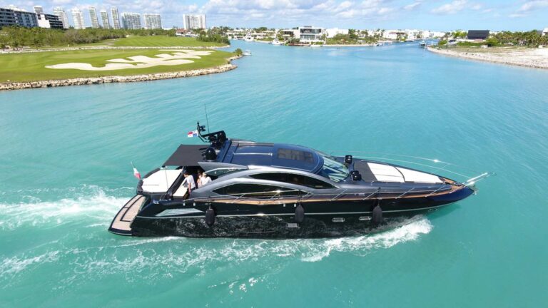 Aerial view of striking all-black 64 ft Sunseeker Truco luxury yacht charter cruising turquoise Cancun waterway past marina and golf course