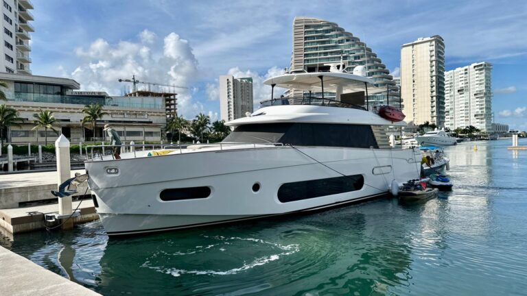 Yate charter de lujo Azimut 2026 blanco 66 ft atracado en la marina de Cancún con jet ski al costado y skyline de la Zona Hotelera al fondo
