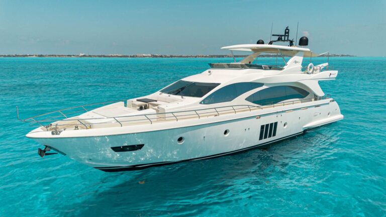 Vista de tres cuartos de proa del yate charter de lujo Azimut Privacy 84 ft fondeado en aguas turquesas cristalinas del Caribe cerca de Isla Mujeres Cancún