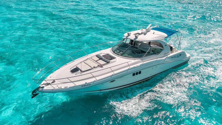 Aerial view of the 44 ft Sea Ray Otelo yacht cruising over turquoise Caribbean shallows off Cancun with blue bimini up for luxury private yacht charter