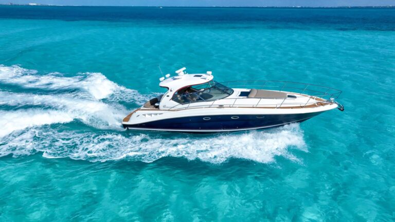 Aerial side shot of 45 ft Sea Ray Sundancer Humble cruising fast over turquoise Caribbean water near Cancun on a family yacht charter rental.