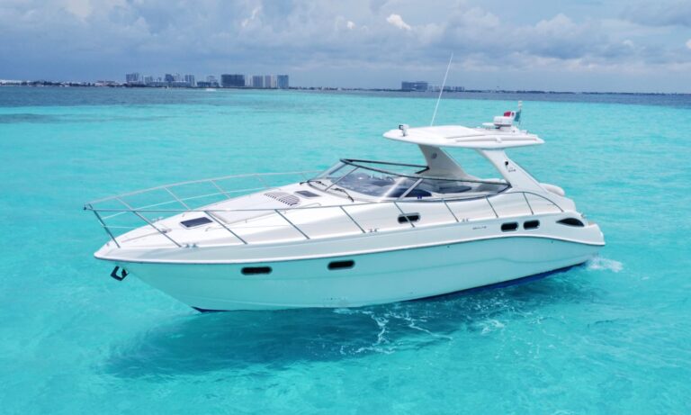 35 ft Sealine S43 Adictivo sport yacht rental anchored in turquoise Caribbean water near Cancun, sleek white hull with hardtop, Cancun hotel zone skyline in background.
