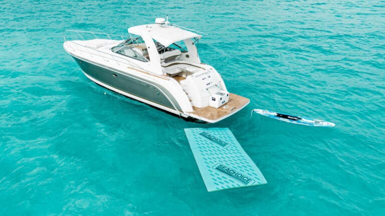 Aerial view of 40 ft Formula White Rum cruiser anchored in turquoise Caribbean with floating mat and SUP paddleboard deployed off teak stern platform.