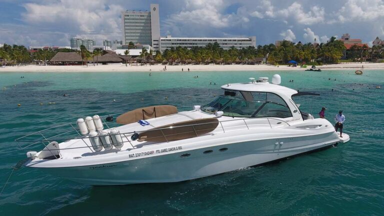 51 ft Sea Ray Five Hundred luxury yacht Yaakun anchored in turquoise Caribbean water off Cancun beach with snorkel gear on bow and crew at stern.