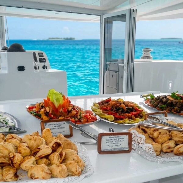 Catamaran buffet of fresh empanadas, shrimp salad and seafood platters set by the helm above turquoise Caribbean water.