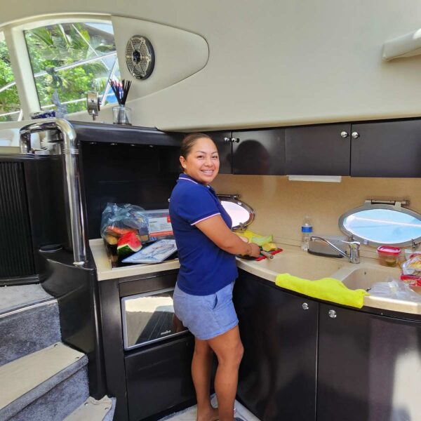 Crew member preparing fresh ingredients in the compact galley kitchen of a chartered boat in Cancun.