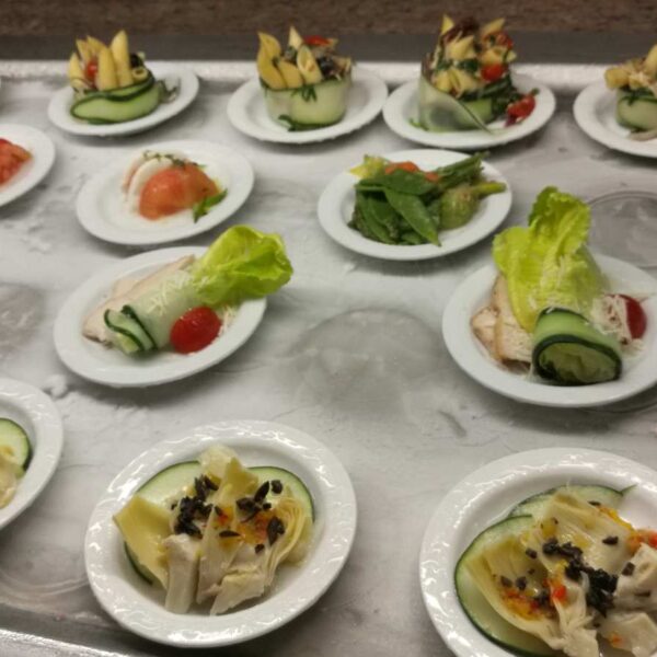 Tray of plated appetizer bites with cucumber, chicken, tomato and greens prepared fresh in the boat galley.