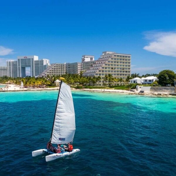 Small sailing catamaran cruising the turquoise Caribbean off Cancun hotel zone, perfect water toy fun on a yacht day tour.