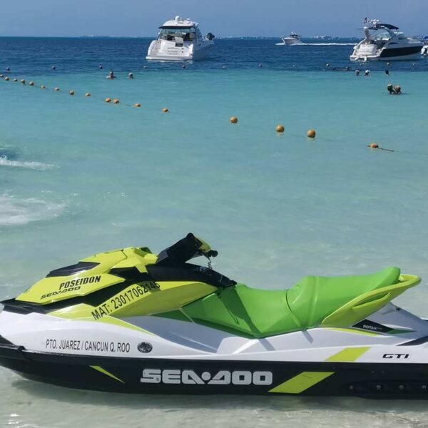 Green Sea-Doo GTI jet skis and wave runners ready on the clear shallows of a calm Cancun beach launch point.