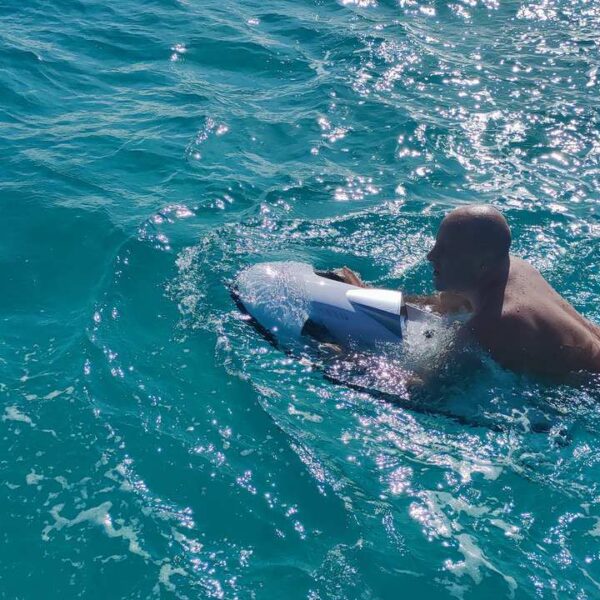 Swimmer powers through bright turquoise water gripping an underwater seabob scooter, a fun water toy during a Cancun yacht outing.
