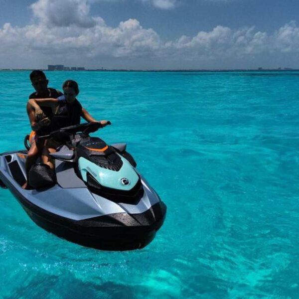 Couple cruises a teal Sea-Doo jet ski across vivid turquoise Caribbean shallows near Cancun, a top yacht tour water toy.